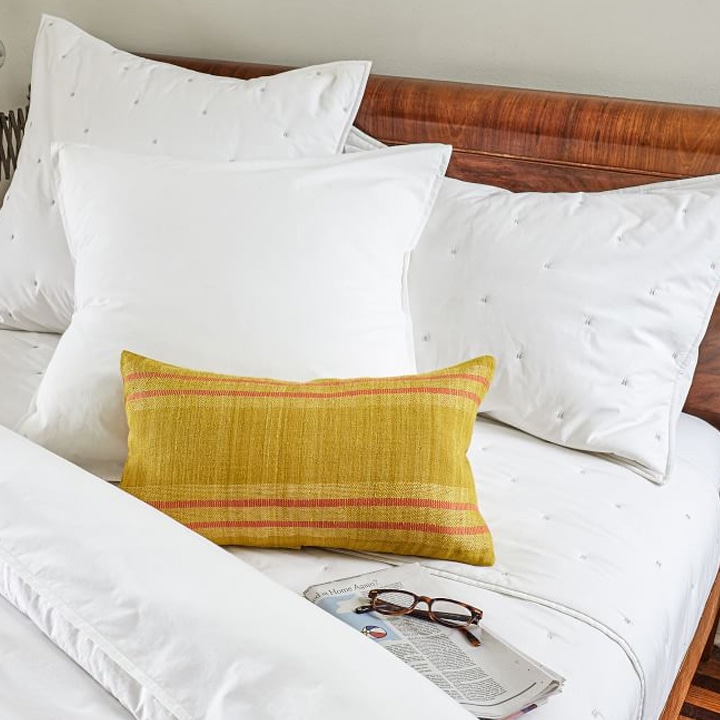 white bedding with bright yellow and orange sham