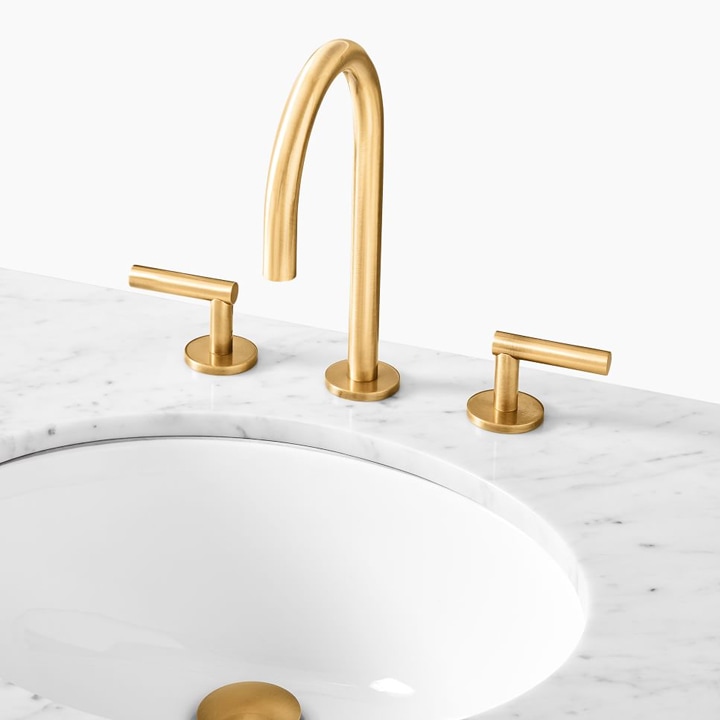Brass sink faucet on marble countertop.