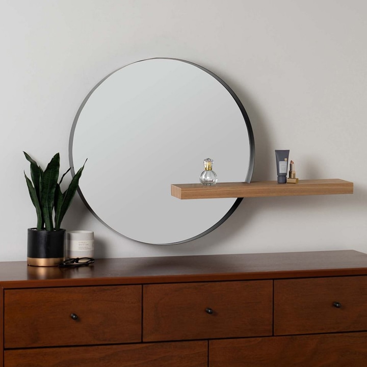 Large circular wall mirror with a wood shelf.