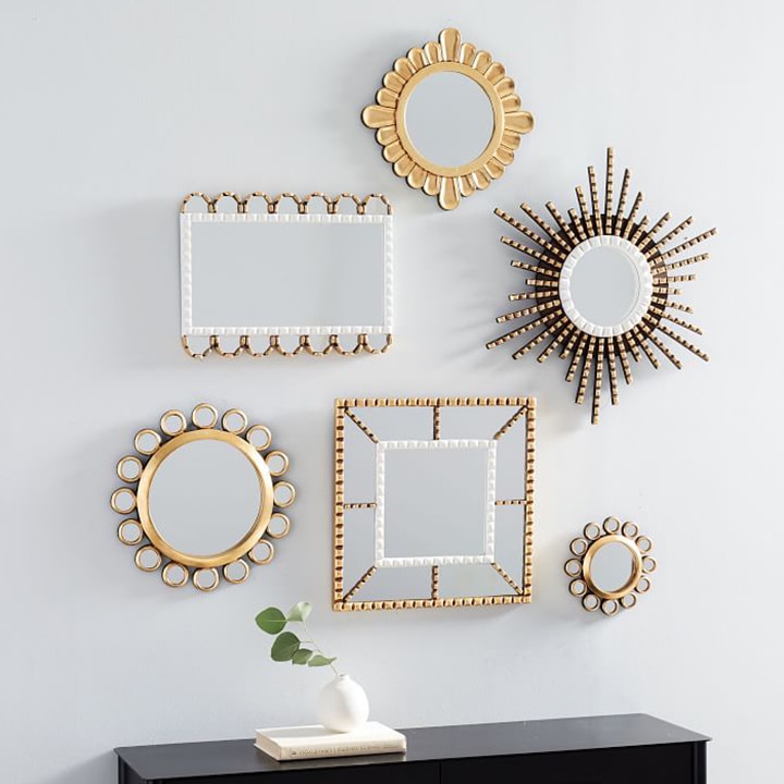 Multiple decorative mirrors hanging on wall. 