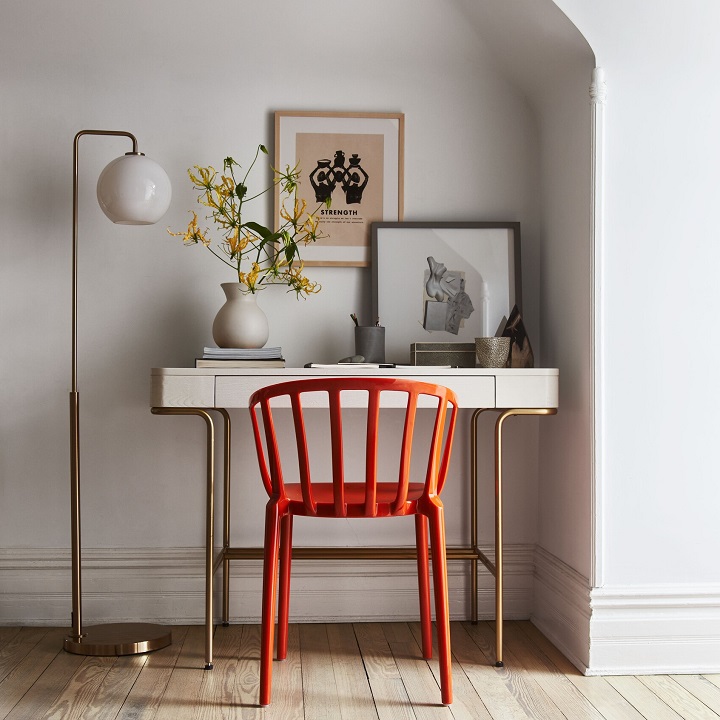 Small white desk with bold color desk chair and a floor lamp.