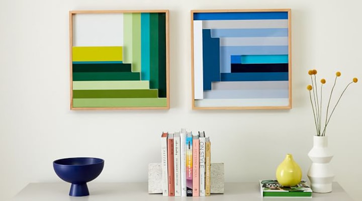 Two colorful hanging art pieces on a wall 