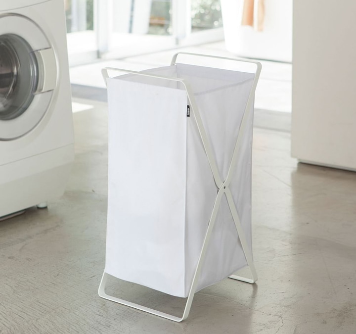 Folding white laundry hamper in laundry room.