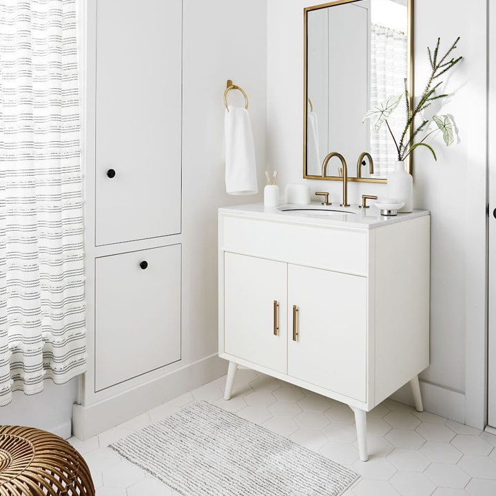 White bathroom with white vanity and gold accents.