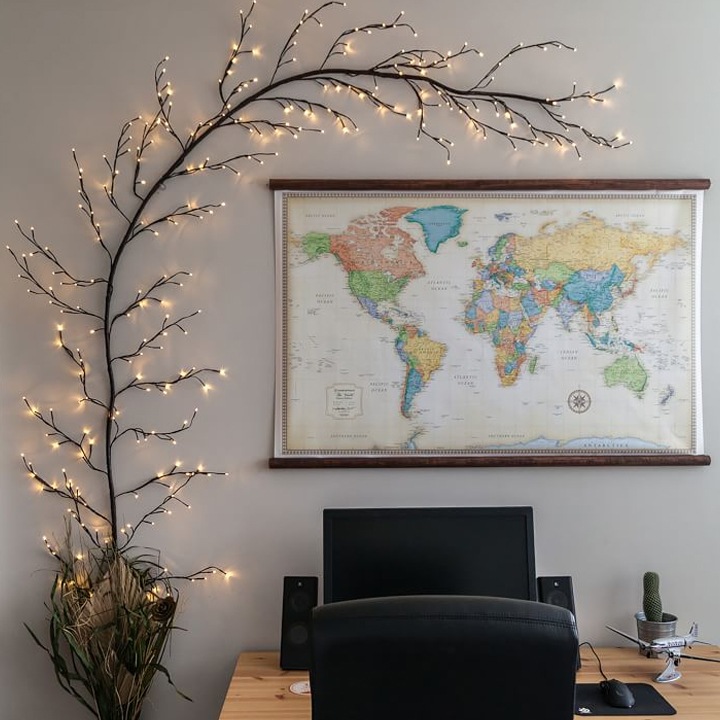 branch with christmas lights attached to wall over a world map