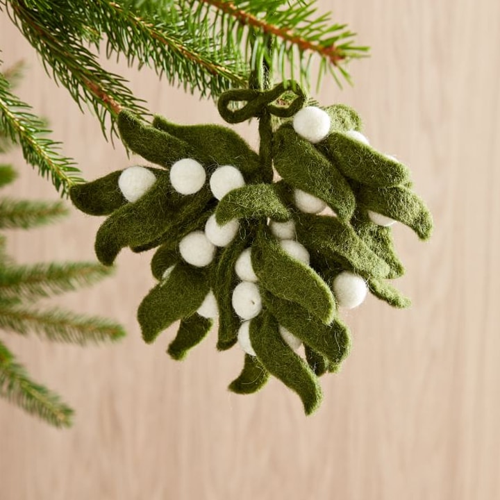 green and white felted mistletoe ornament hanging from christmas tree
