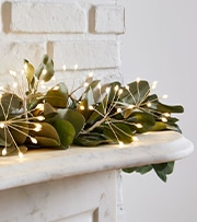 green garland with white lights on mantel