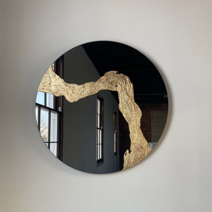 Round tinted mirror with abstract gold design.
