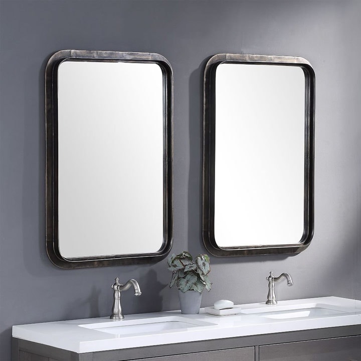 Two metal framed mirrors above bathroom vanity.