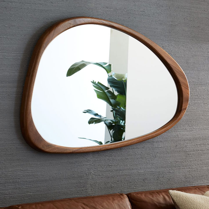Asymmetrical mirror on wall above sofa.