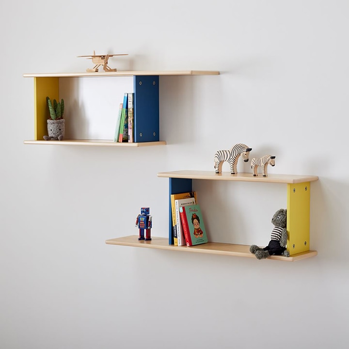 Two wooden shelves on a wall with various books and toys