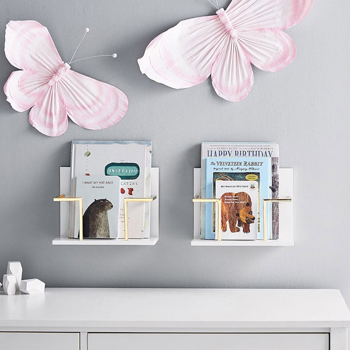 Pink butterfly decorations placed on a wall, with two small bookshelves underneath