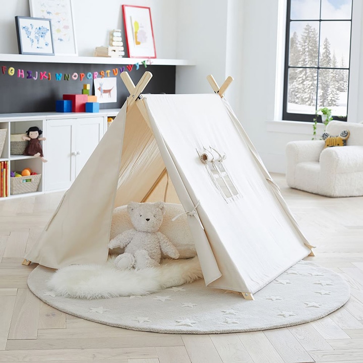 Stuffed bear and pillow placed in a play tent on top of a rug
