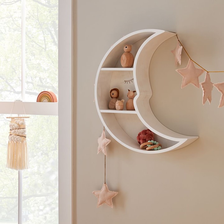Moon-shaped shelf on a wall holding various toys