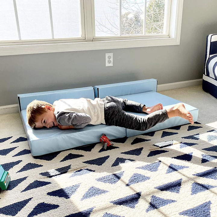 Child laying on a blue foam mini couch