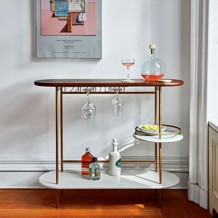 Three tiered bar cart with decanter and glasses on top. 