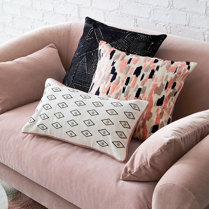 Velvet blush loveseat with pattern pillows. 