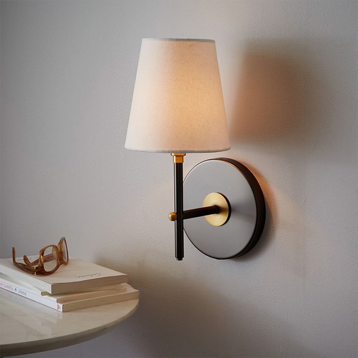 Black and bronze mid-century wall sconce with light lamp shade.
