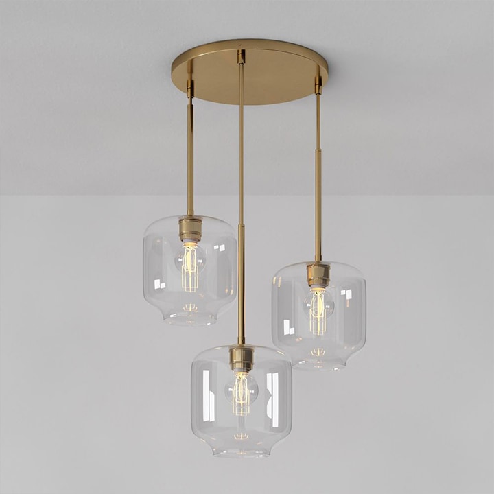 Brass multi-chandelier with three lights hanging from ceiling.