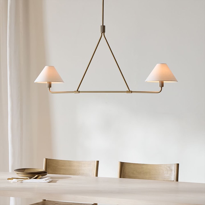 Architectural brass pendant with two white lamp shades.