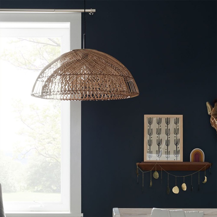 Dome-shaped wicker pendant hanging in navy room.