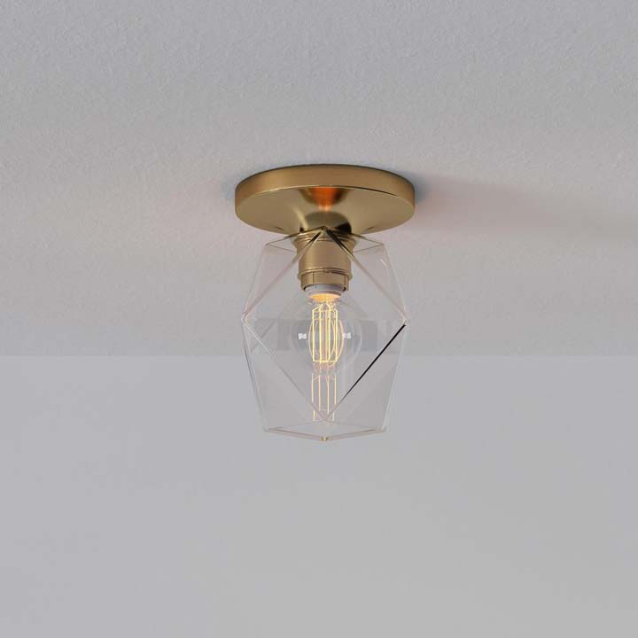 Brass flushmount with geometric glass shade mounted on ceiling.