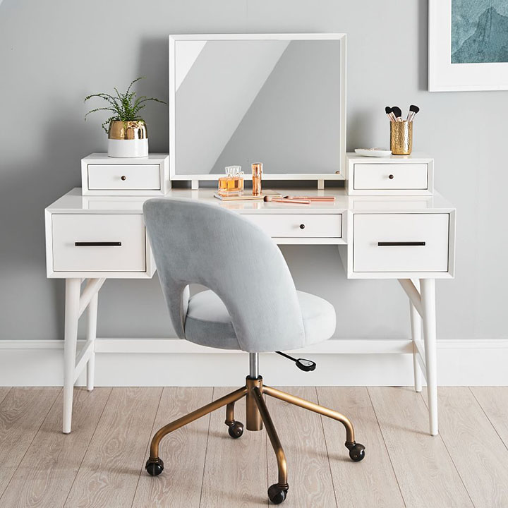 White makeup vanity with gray velvet chair. 