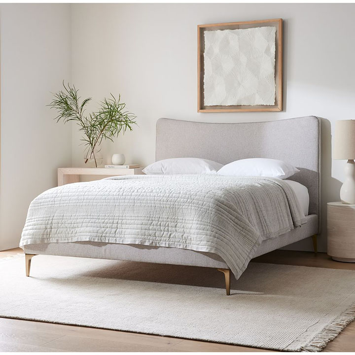 Gray bedframe with gray quilt and gray area rug. 