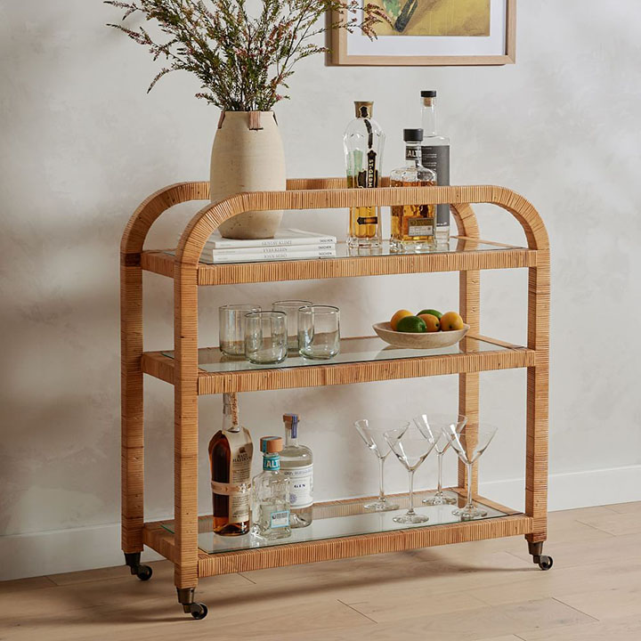 Wood bar cart with martini and cocktail glasses and assorted liquor. 