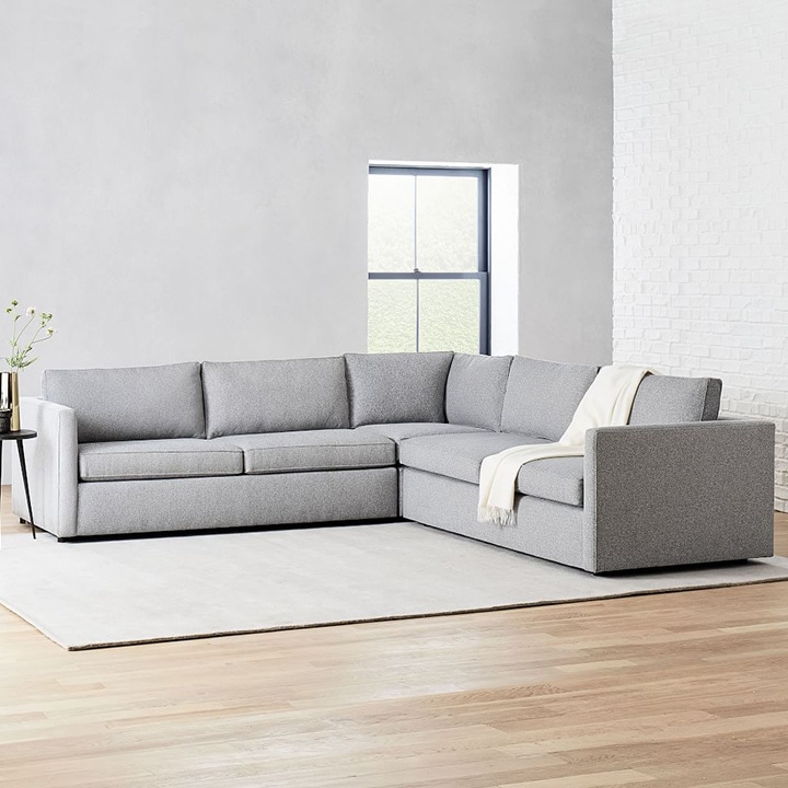 Medium gray sectional with light gray walls and area rug. 