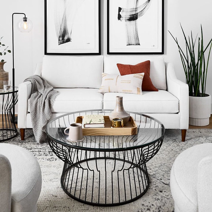Black coffee table and framed pictures with white sofa and white paint. 