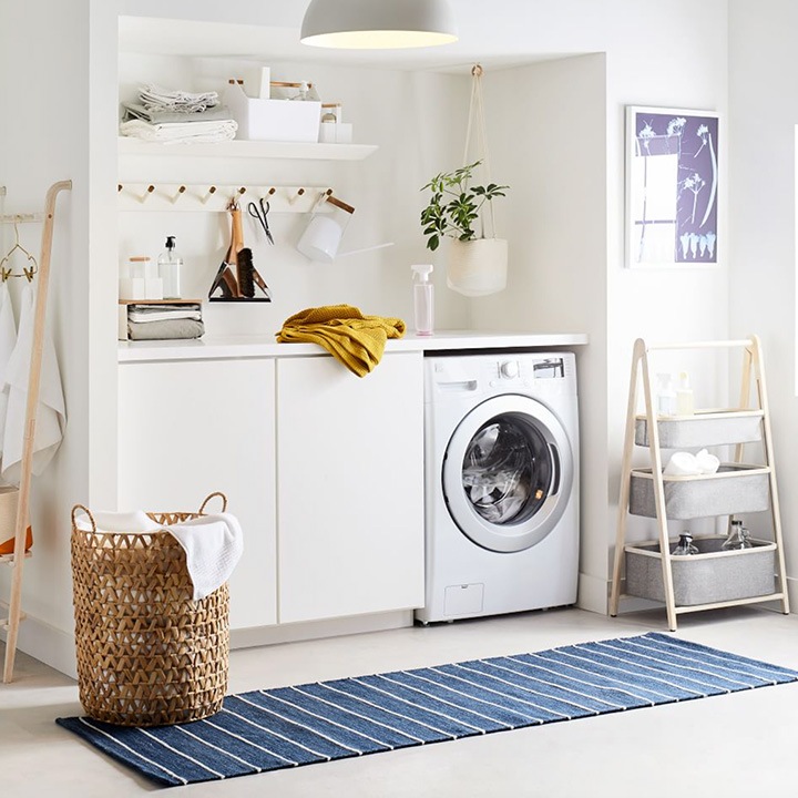 Laundry room with washer, clothing rack, hamper and storage bins.