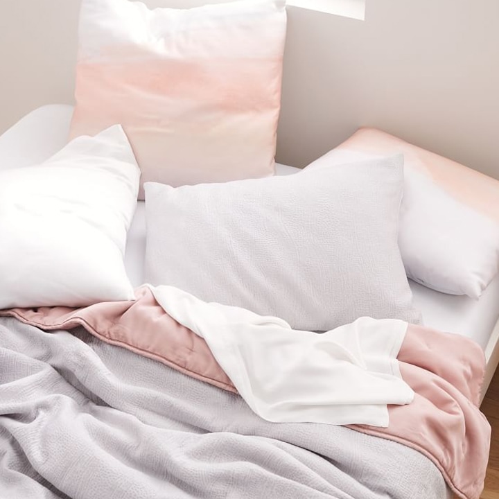 unmade bed with pink watercolor TENCEL™ sheets and pillows