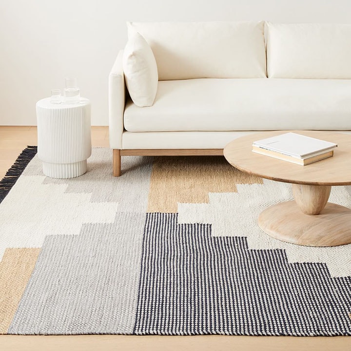 White sofa with white side table, patterned rug and natural wood coffee table. 