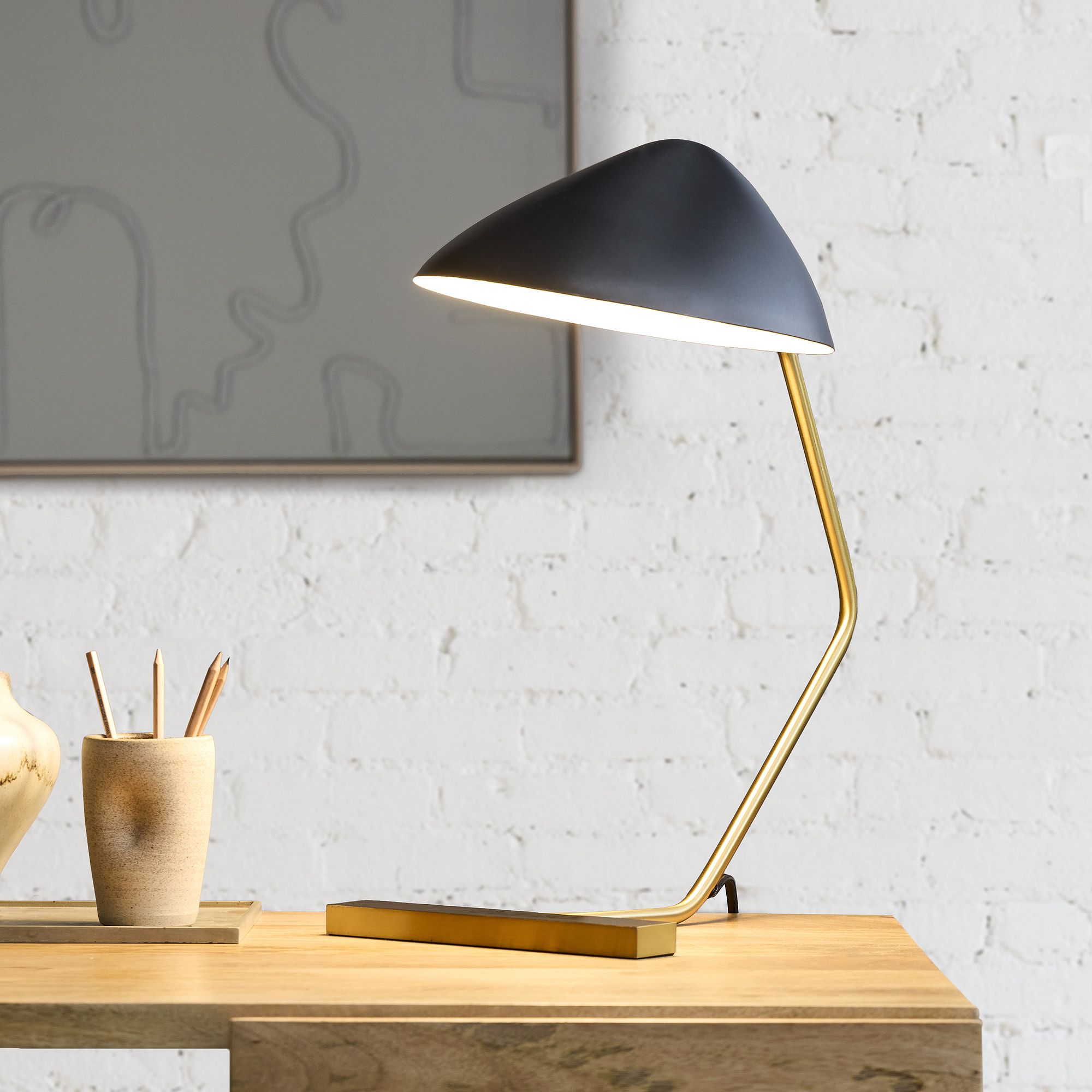 Black and Gold Curvilinear Mid-Century Table Lamp on a Dark Wooden Desk