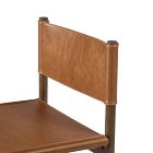 Top edge of a tan leather chair back over a wooden frame, with posts at each end