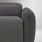 Close-up of the soft upholstery and seam along the arm of a gray armchair.