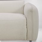 Close-up of the armrest and stitching on a cream-colored armchair.