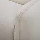 Close-up of the seam line and corner of an off-white upholstered armchair.