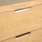 Close-up of a drawer front with a slim metal handle on light wood