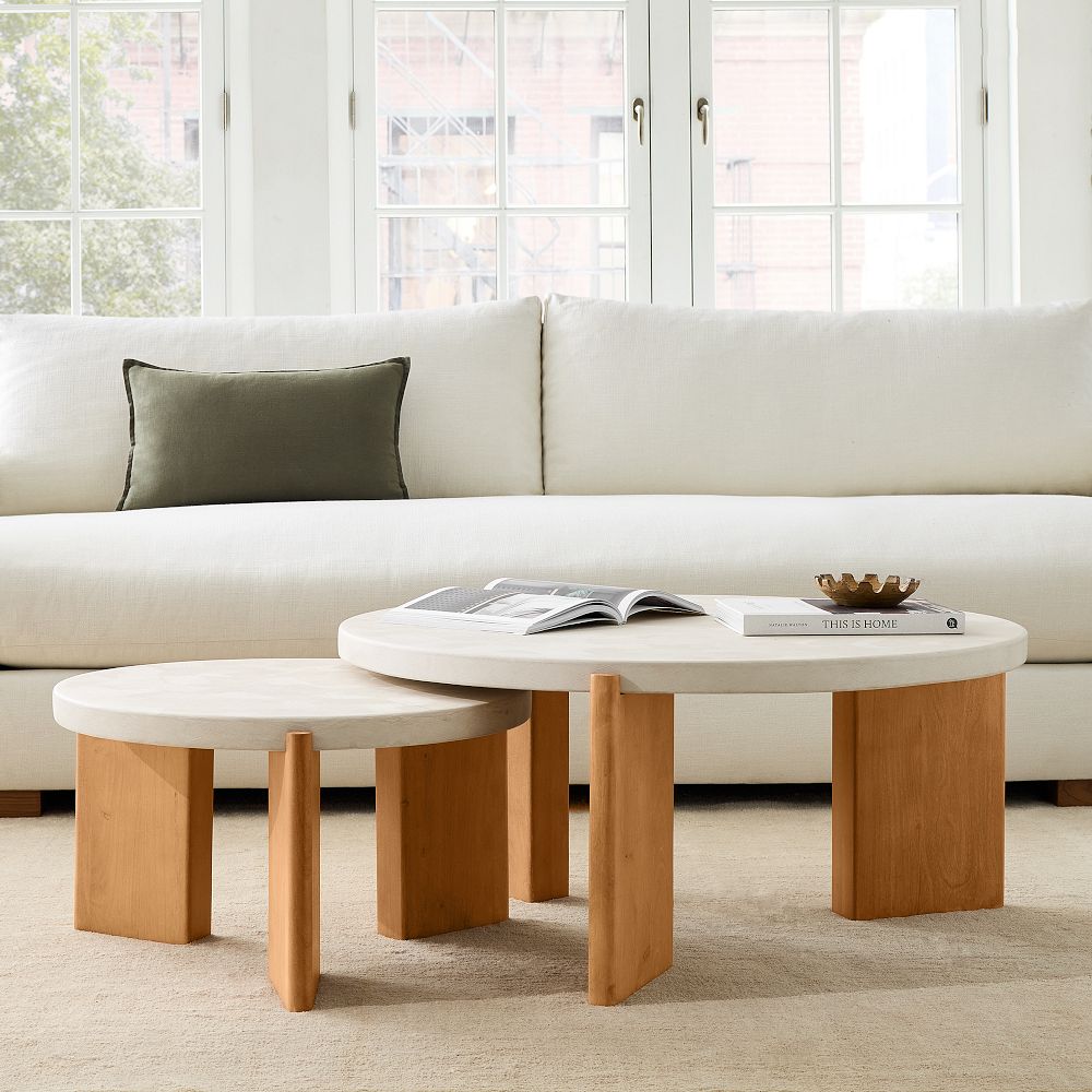 Set of round nesting coffee tables with white top and thick wooden legs in a living room