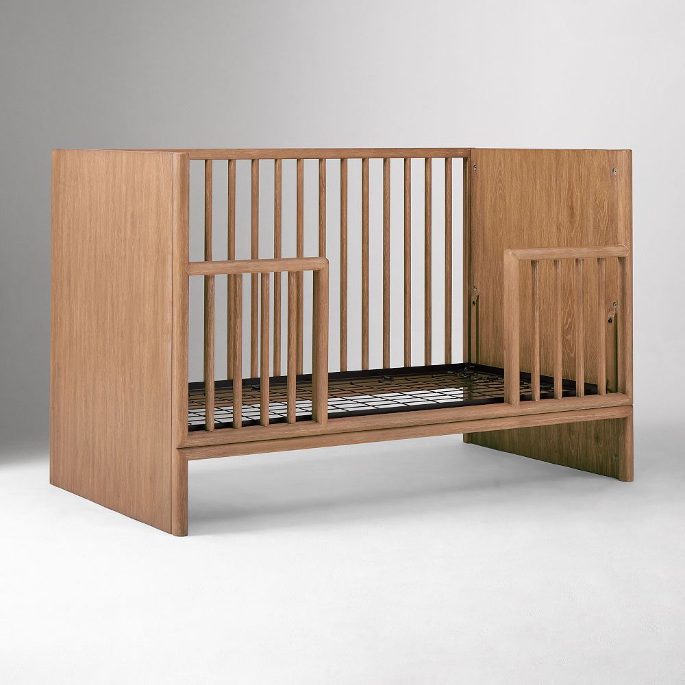 Three-quarter view of crib with internal rails and mattress