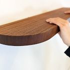 Hands mounting curved-edged shelf on wall