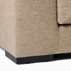 Close-up of the base and leg of a beige sofa.