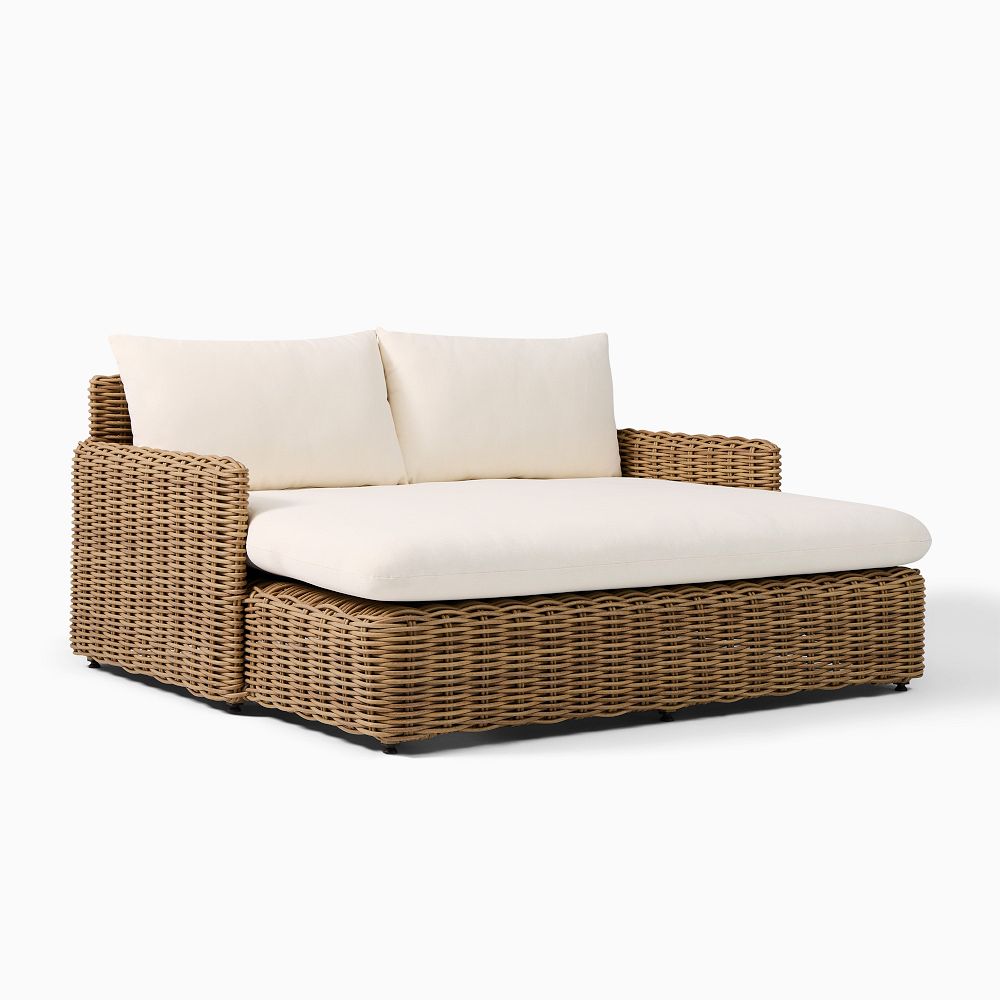 Cozy outdoor wicker sectional sofa with thick cream cushions and woven rattan frame on low feet