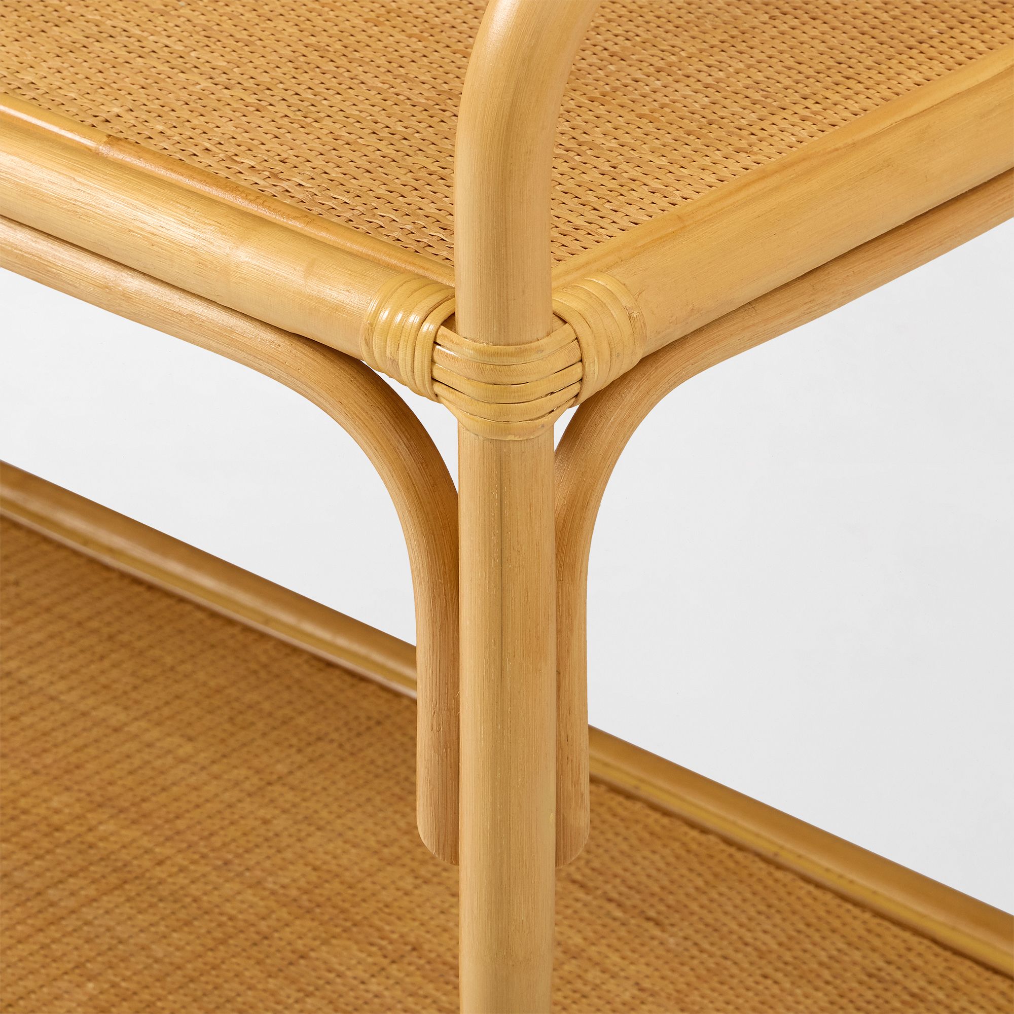 Joint where vertical leg meets shelf on curved rattan shelf