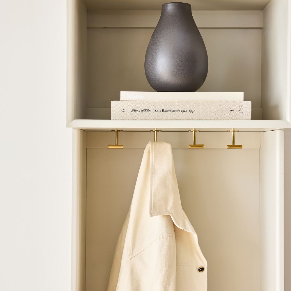 Decorative grey vase and stacked books on top shelf of wardrobe system