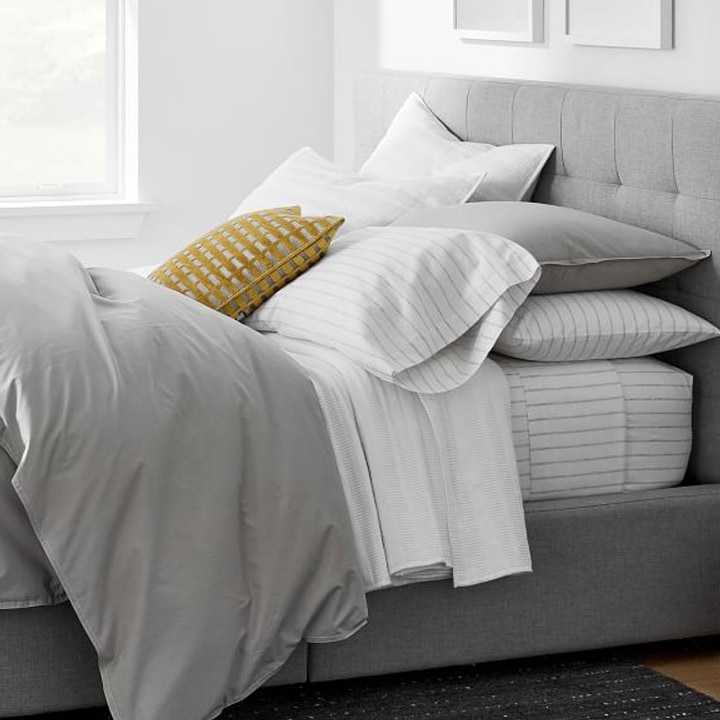 gray and white bedding with yellow sham