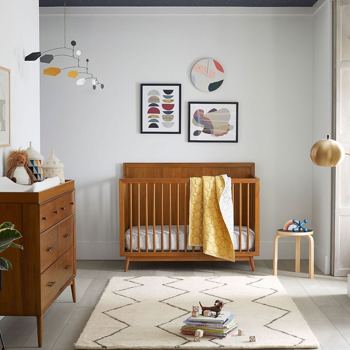 Mid-century modern nursery with wooden crib and changing table.