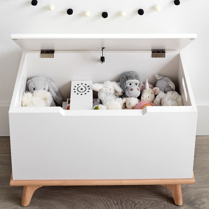 Open white toy storage box with stuffed animals inside.